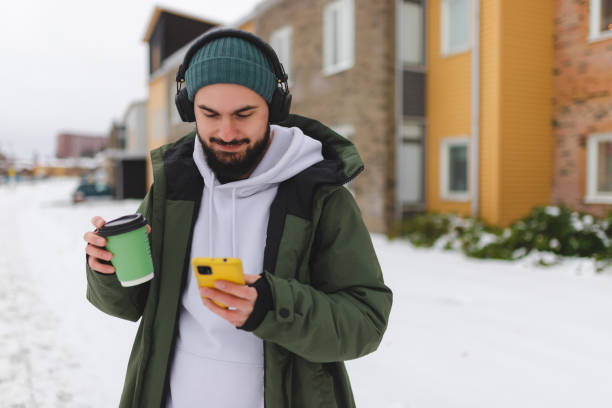 istock Handsome young man using his phone outdoors while wearing headphones 1450037285
