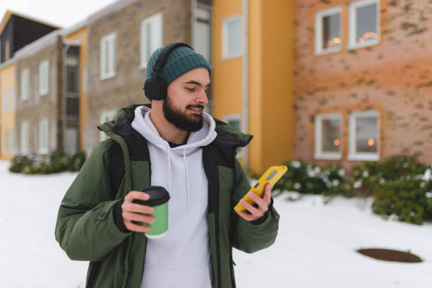 istock Handsome young man using his phone outdoors while wearing headphones 1450037291