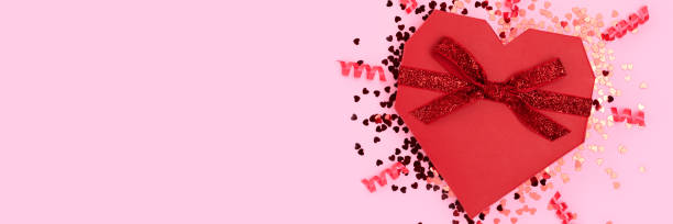 istock Banner with red gift box in a heart shape tied with glittering ribbon. 1450037814
