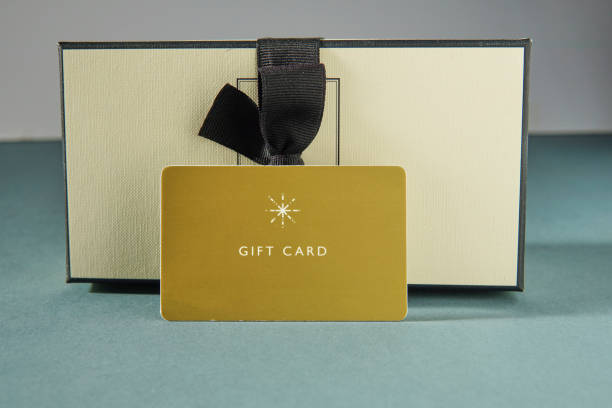 istock Yellow gift card and a gift box against green background. gift card or gift 1450039183