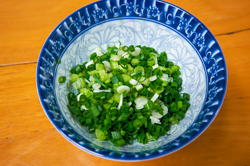 A bowl of fresh minced green onions closeup
