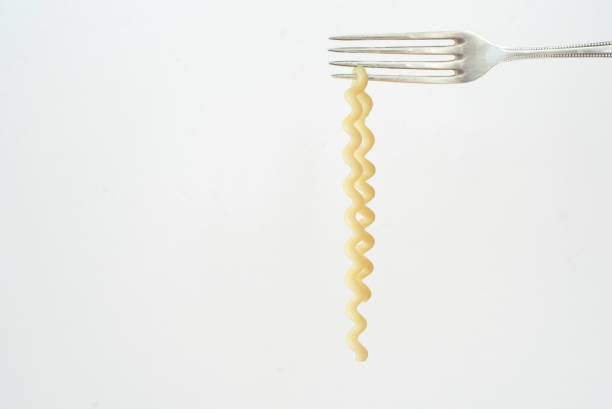 italian pasta hanging from a silver fork, isolated on white background,free copy space