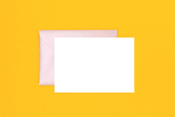 istock Clean white paper mockup and silver glittering envelope on a yellow background. 1450039767