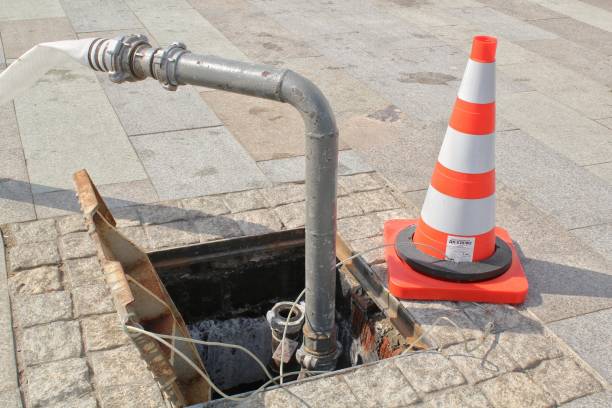 istock Open manhole, construction traffic warning cone and metal pipe on sidewalk 1450039851