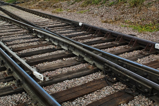 Railway line junction tracks. Railroad travel, tourism. Transportation concept. Iron detail over dark stones. Heavy industrial landscape. Technology modern infrastructure development. Close up