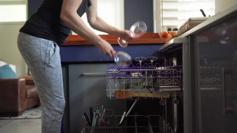 Woman unpacking wine glasses from her dishwasher at home