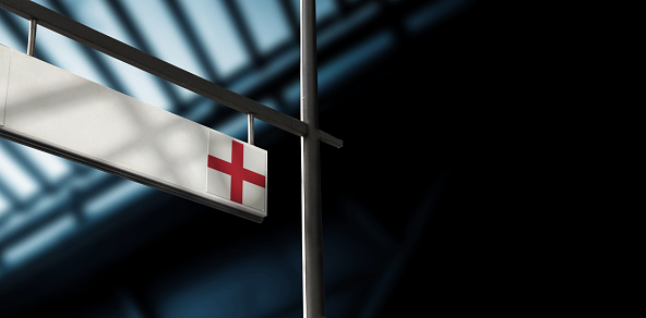 Flag of England on airport departure information board. Close-up. Roof construction in the background. Blue color. Horizontal orientation. Ne people. Copy space.