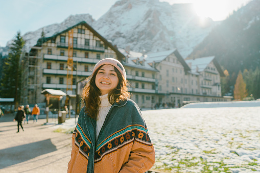 Young Caucasian woman  standing on the background of resort on   Lago di Braies in winter