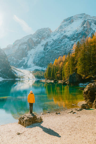 woman  standing on rock on the background of  lago di braies in winter - travel vertical tourist switzerland imagens e fotografias de stock