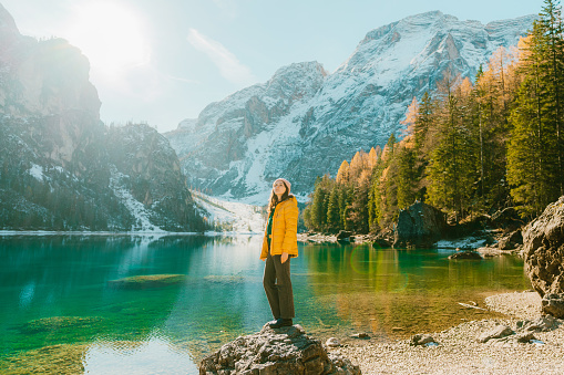 Young Caucasian woman  standing on rock on the background of  Lago di Braies in winter