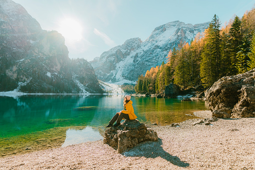 Young Caucasian woman  sitting on the background of  Lago di Braies in winter