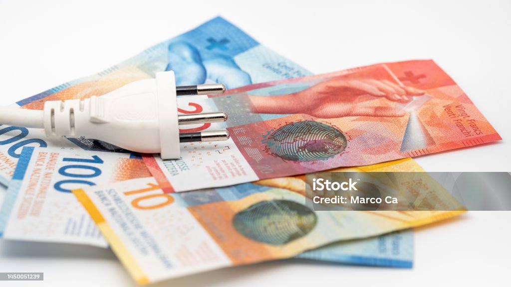 a power plug on some swiss franc banknotes A white J-type power plug with a power cable lies on top of some Swiss banknotes, on a white background. The picture shows banknotes with denominations of 10 francs, 20 francs and 100 francs. Bills of the current 9th series of banknotes. The Swiss Franc is the currency of the Swiss Confederation and the Principality of Liechtenstein. The swiss franc (CHF) is issued by the swiss national bank (SnB). Currency Stock Photo