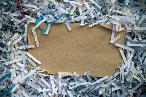Hand holding shredded paper strips in a basket shredders
