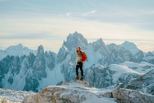 Young Caucasian woman with backpack hiking  in snow-covered Dolomites in winter