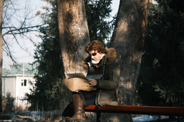 istock Woman is using laptop in winter nature park 1450052946