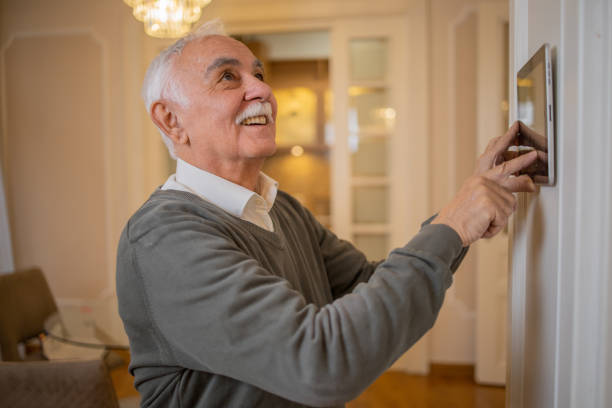 istock Senior man adjusts the temperature at home with a device on the wall 1450054867