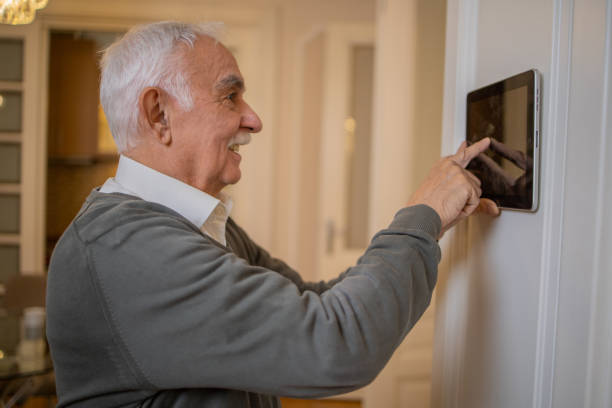 istock Senior man adjusts the temperature at home with a device on the wall 1450054875