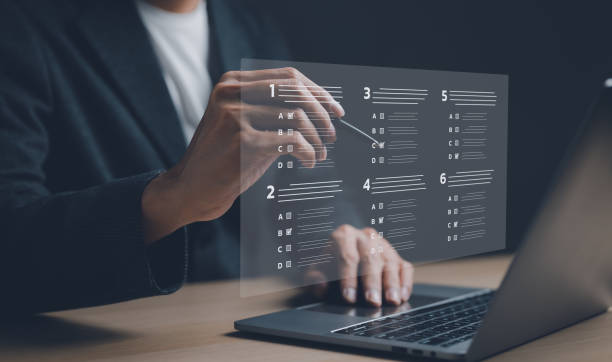 istock Businessman with evaluating questionnaire on online laptop computer. assessment survey online, choose correct answer in test, questions test, online exam, quiz knowledge, filling out an survey form. 1450058573