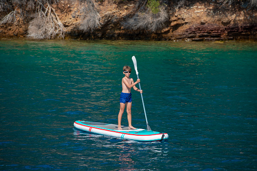 Boy using SUP board with paddle.