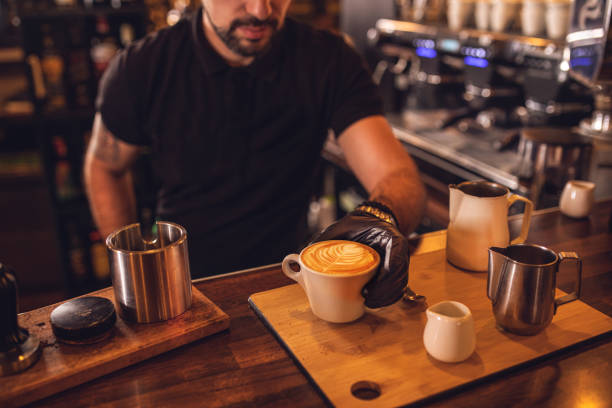 Man preparing coffee at table in cafe