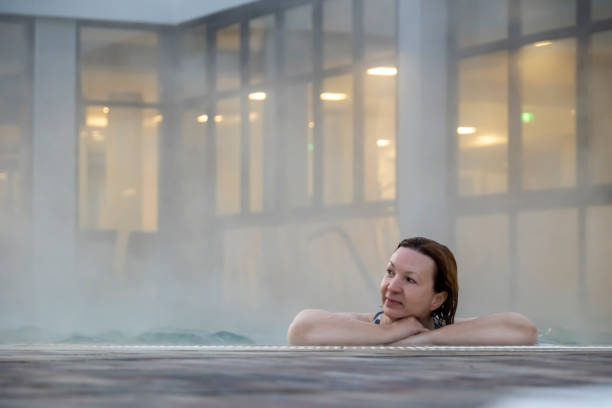 Calm waters, calm mind Shot of a mid-adult woman relaxing in the thermal pool at a spa thermal pool stock pictures, royalty-free photos & images