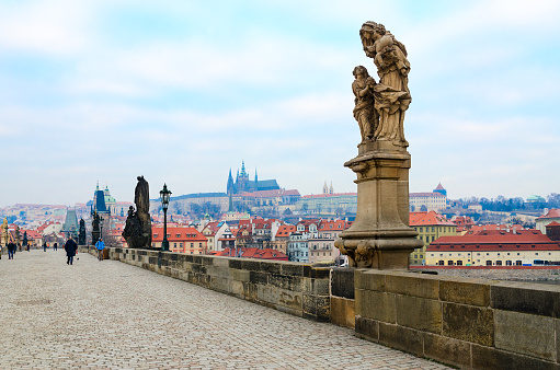 Prague, Czech Republic - January 22, 2019: Sculptural compositions of Charles Bridge. Saint Anne, mother of Virgin Mary, patroness of marriage, babies, mothers and widows (1707). Unidentified tourists are on bridge