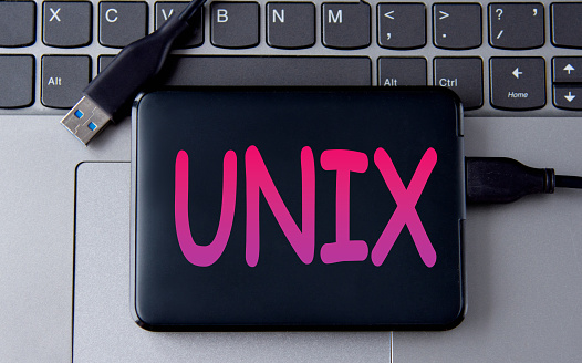 UNIX {UNiplexed information Computing System) - acronum on an external drive in gray letters on the background of a laptop. Internet concept