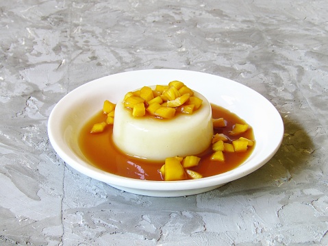 Potato pudding with jackfruit coconut sugar syrup on a white plate on a gray background