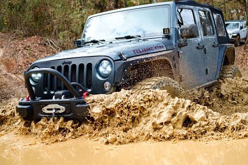 Rome, United States – October 25, 2020: A modified Jeep Rubicon JK driving through mud.