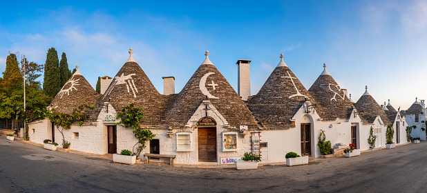 Alberobello, Italy - October 10, 2022: Trullo houses with whitewashed symbols. The drystone huts with conical roofs are traditional in Puglia.
