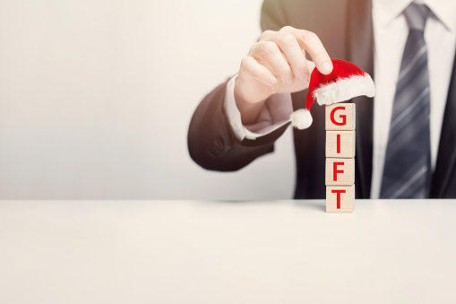 Four wooden cubes with sign gift in Christmas hat, holiday, New Year business bonus concept