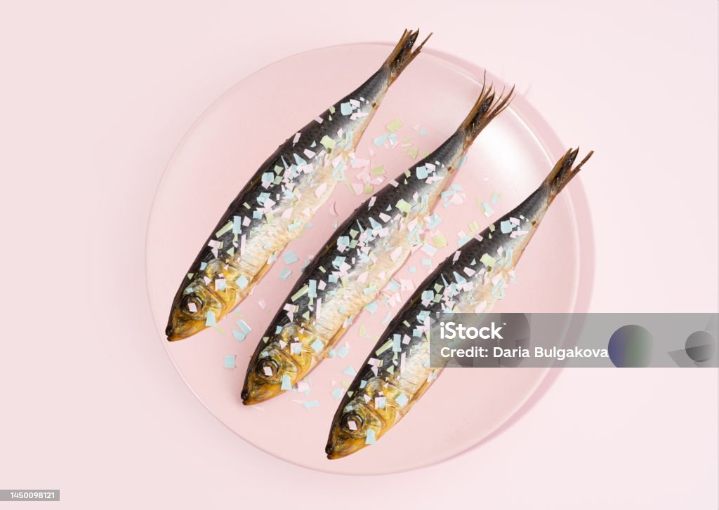 Fish covered microplastic on a pink plate. Impact of micro plastic on the food chain. Concept of environmental damage. The idea of microplastic pollution Fish covered microplastic on a pink plate. Impact of micro plastic on the food chain. Concept of environmental damage. The idea of microplastic pollution. Alertness Stock Photo