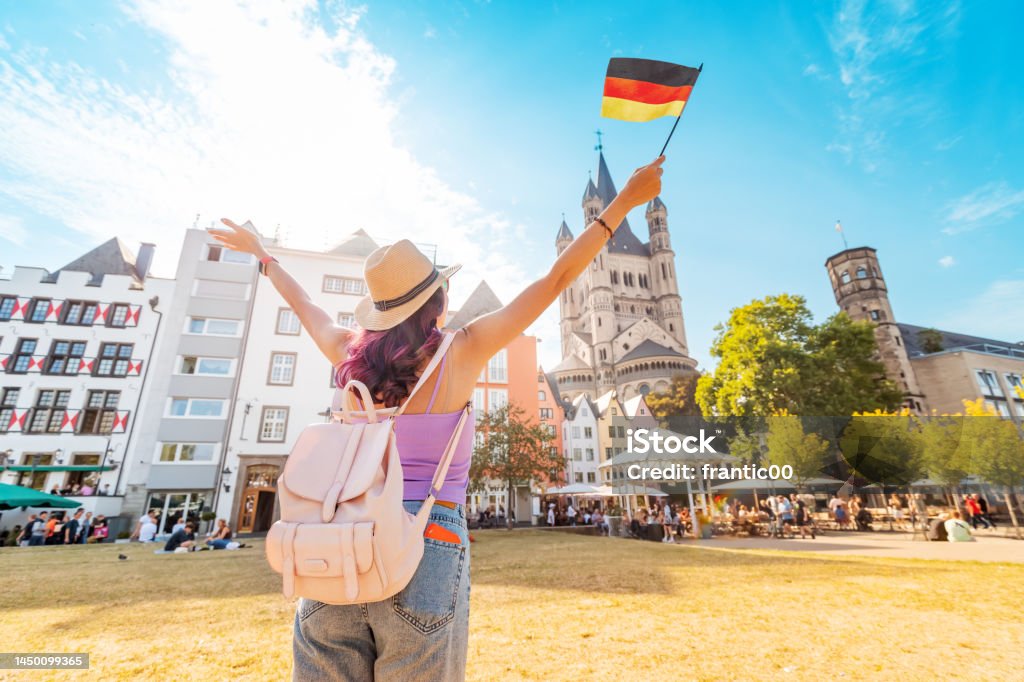 A young happy tourist or student girl with a German flag at the old town or Altstadt in Cologne fish market square. Studying language abroad and traveling concept Germany Stock Photo