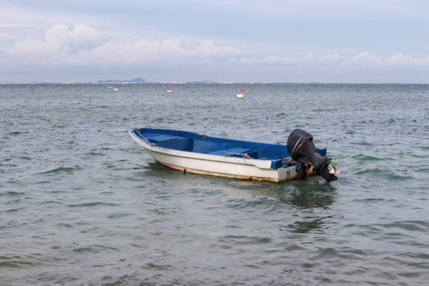 istock Small white paint motor boat and blue paint inside with nobody inside floating somewhere at the sea. 1450110175