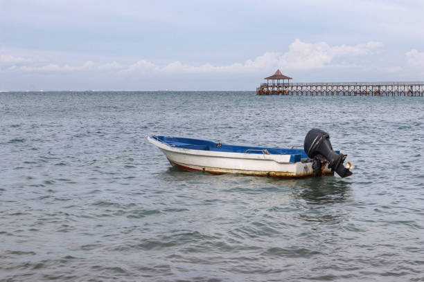 istock Small white paint motor boat and blue paint inside with nobody inside floating somewhere at the sea. 1450110185