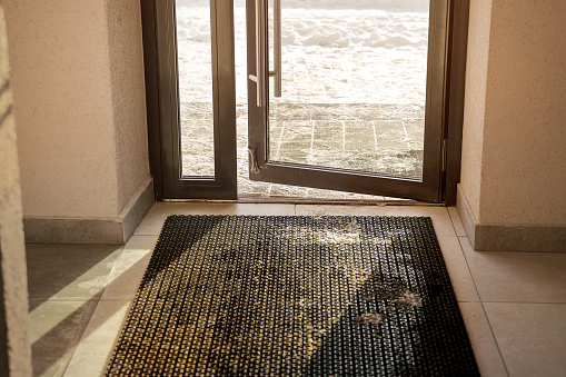 Muddy rubber doormat mounted on tiled floor at house entrance