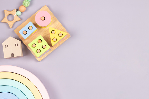 Baby kid toys on light gray background. Sustainable early childhood development baby stuff and natural pastel color wooden toys. Top view, flat lay.