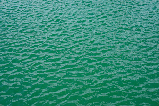 Background texture or small ripple waves in the calm green ocean water