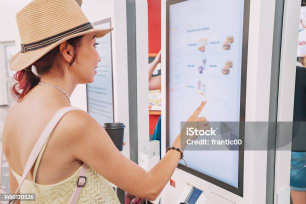 A Female Customer Uses A Touchscreen Terminal Or Selfservice Kiosk To Order At A Fast Food Restaurant Automated Machine And Electronic Payment Stock Photo - Download Image Now