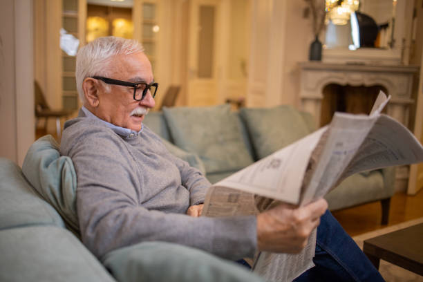 istock Senior man sitting and reading newspaper at home 1450123647