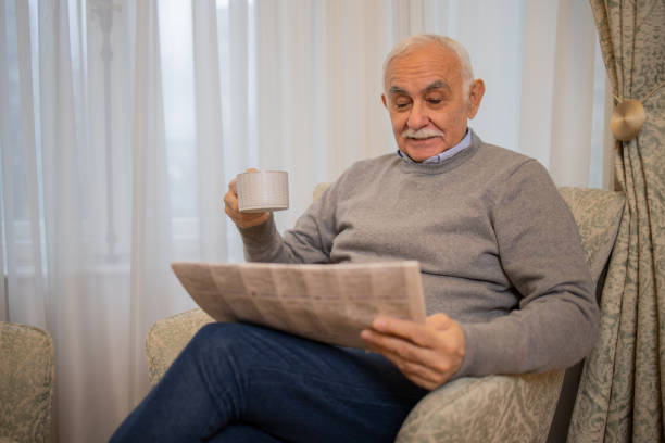 istock Senior man sitting and reading newspaper at home 1450123658