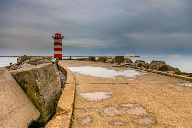 Aerial view of a small lighthouse and breakwater.