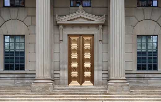 Entrance to classical style office building with stone columns and brass colored door
