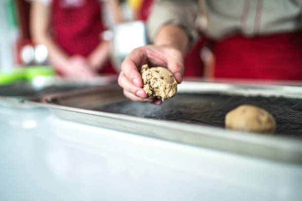 Man placing a cookie dough in a baking sheet during a cooking class