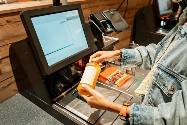 eine kundin scannt und bezahlt eine flasche saft aus einem supermarkt in einem automatisierten selbstbedienungskassenterminal - markt verkaufsstätte stock-fotos und bilder