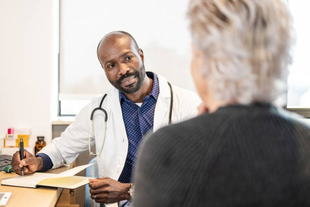 black mid adult male doctor with notepad and pen talking to a patient - doctor electronic organizer healthcare and medicine patient imagens e fotografias de stock