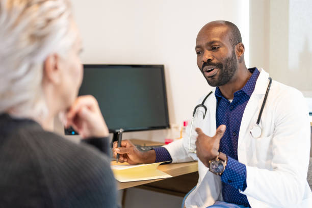 black mid adult male doctor with notepad and pen talking to a patient - doctor electronic organizer healthcare and medicine patient imagens e fotografias de stock