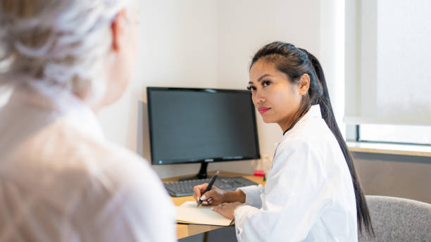 asian female doctor with notepad and pen talking to a patient - doctor electronic organizer healthcare and medicine patient imagens e fotografias de stock