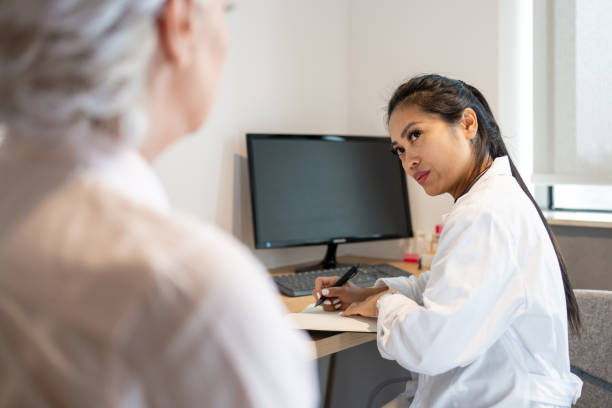 asian female doctor with notepad and pen talking to a patient - doctor electronic organizer healthcare and medicine patient imagens e fotografias de stock