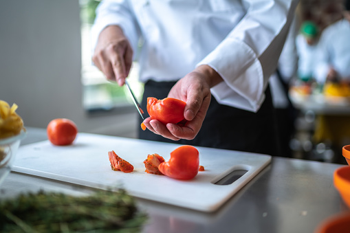 Chef chopping a tomato in a commercial kitchen